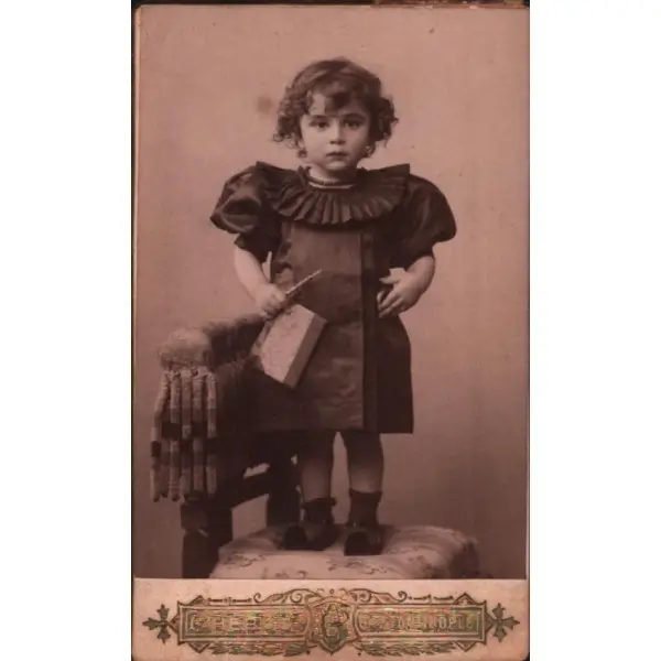 Defter ve kalemiyle poz veren sevimli kız çocuğunun kabin fotoğrafı, Phebus Fotoğrafhanesi- Constantinople, 6x11 cm