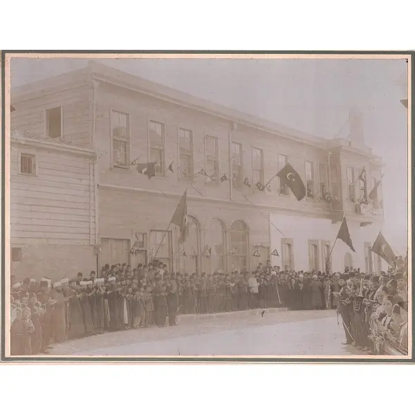 Türk bayrakları asılı bina önünde dua ederken poz veren devlet erkânı, bando takımı ve minikler, paspartu: 30x36 cm