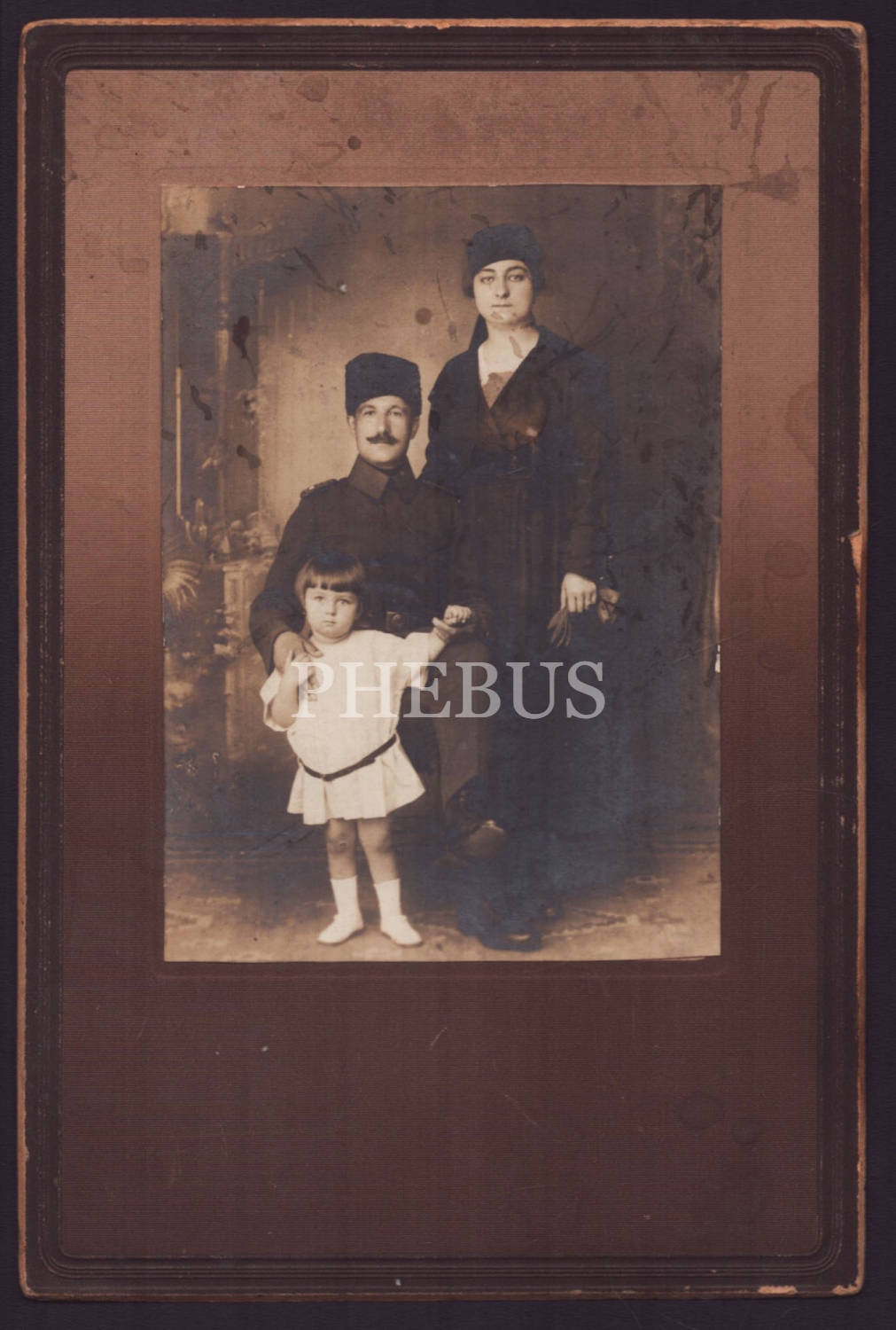 Kalpaklı Türk subayının eşi ve minik kızıyla birlikte aldırdığı stüdyo kabin fotoğrafı, ithaflı ve imzalı, paspartusuyla birlikte 16x23 cm...